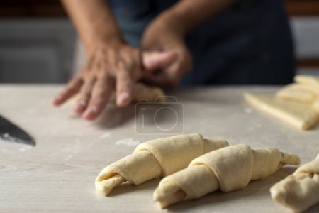 Téléchargez les photos : Mains de boulangers femmes et hommes faisant la pâte pour les croissants étape par étape, pétrissant et assemblant les croissants prêts à cuire - en image libre de droit