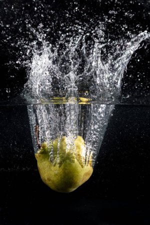 Téléchargez les photos : Fruits tombant dans l'eau formant une éclaboussure fraises citron oranges pommes poires avec un fond noir et de l'eau dans l'air - en image libre de droit