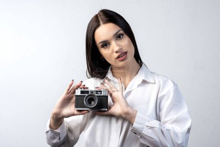Téléchargez les photos : Jeune femme latine avec un appareil photo dans sa main souriante et heureuse de photographier son style de vie - en image libre de droit