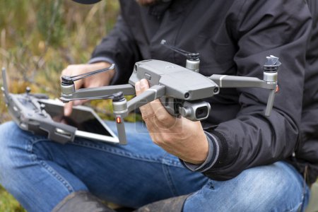 Téléchargez les photos : Jeune homme volant et conduisant un drone au milieu d'un champ Télécommande du drone entre les mains de l'homme Véhicule aérien sans pilote - en image libre de droit