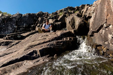 Téléchargez les photos : Jeune voyageur dans les montagnes profitant du grand paysage entre les rochers et la végétation libre observer - en image libre de droit