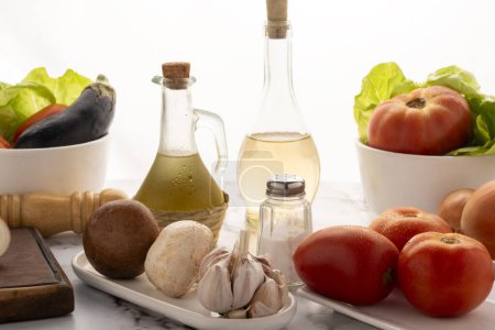 Téléchargez les photos : Mise en place sur la table avec assortiment de légumes en vaisselle blanche avec vinaigre d'huile de poivre et sel pour salade et repas végétariens et végétaliens - en image libre de droit