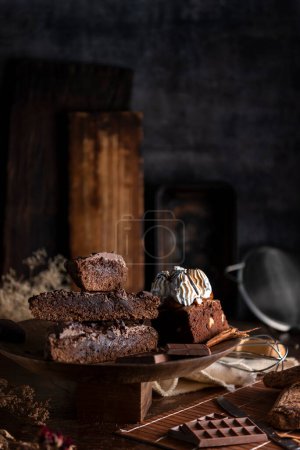 Téléchargez les photos : Gâteau au brownie au chocolat avec sauce à la crème sur la table avec des ingrédients de barre de chocolat et des ustensiles de cuisine - en image libre de droit