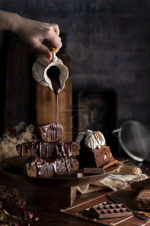 Téléchargez les photos : Gâteau au brownie au chocolat avec sauce à la crème sur la table avec des ingrédients de barre de chocolat et des ustensiles de cuisine - en image libre de droit