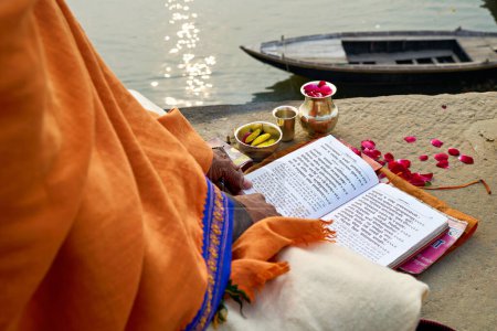 Téléchargez les photos : L'Inde. Varanasi Benares Uttar Pradesh. Un homme lisant les textes sacrés de l'hindouisme et priant près du Gange au lever du soleil - Date : 03 - 01 - 2023 - en image libre de droit