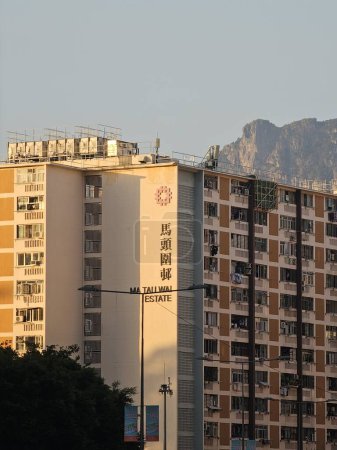 Photo for Hong Kong, China  November 10 2023: At sunset with yellow and warm light, a public housing estate called Ma Tau Wai Estate in Kowloon with Lion Rock Hill as the background. - Royalty Free Image