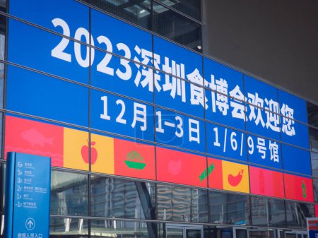 Téléchargez les photos : Shenzhen, Chine - 2 décembre 2023 : Un panneau bleu indiquant "2023 Shenzhen Food Expo" accueille les touristes. L'heure et l'emplacement de l'exposition est également écrit ci-dessous. - en image libre de droit
