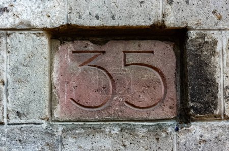 Foto del número de la casa, número treinta y cinco escultura en una piedra roja.