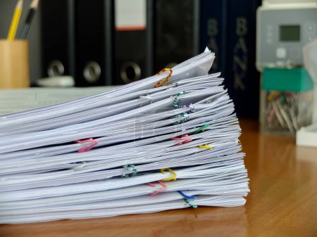 Foto de Una pila de documentos grapados sobre un fondo de carpetas de documentos - Imagen libre de derechos