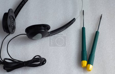 Photo for Headphones and screwdrivers on the table. Concept of companies providing services for diagnostics and repair of electronic devices - Royalty Free Image