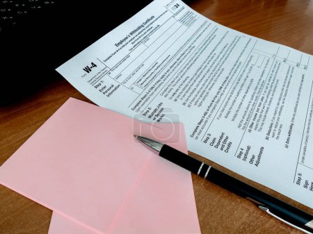 Vista del formulario de impuestos W-4 con cuaderno de lápiz en el escritorio de la oficina. Documentos, concepto de fiscalidad