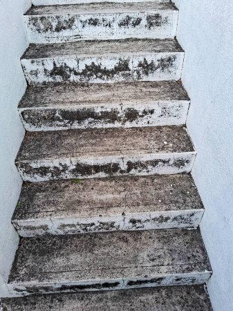 Eine alte Zementtreppe im Freien. Stein, Zementstufen einer alten Treppe mit Verwitterungs- und Zerstörungsspuren. Eine alte Zementtreppe. Schmutzige weiße Zementstufen oder Treppen mit Schlamm und Wasser.