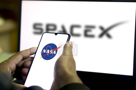 Téléchargez les photos : Logo NASA sur l'écran d'un Smartphone avec un fond flou du logo SpaceX vu affiché.Bangladesh- 15 février 2024. - en image libre de droit