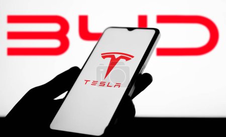 Foto de Enfoque selectivo del logotipo BYD vs Tesla en una imagen de stock de pantalla móvil. Estas empresas son dos fabricantes de vehículos eléctricos gigantes en el mundo: Dhaka, Bangladesh - 6 de abril de 2024 - Imagen libre de derechos
