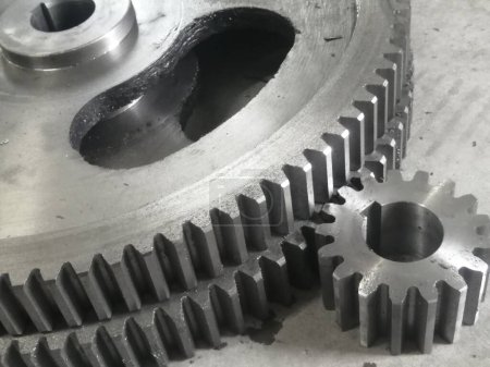 Two metal gears close up.. Mechanical gears. Two large and third, smaller gears are in the foreground. The gears are made of metal using the gear hobbing method. Larger gears have holes to make them lighter.