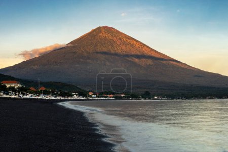 Téléchargez les photos : Lever de soleil coloré tôt le matin sur la plage de sable noir du village d'Amed à Bali surplombant le magnifique volcan Agung en Indonésie - en image libre de droit