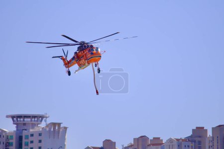 Photo for A firefighting helicopter descends for landing, framed by towering apartment buildings in the background, merging urban landscapes with emergency aviation. - Royalty Free Image
