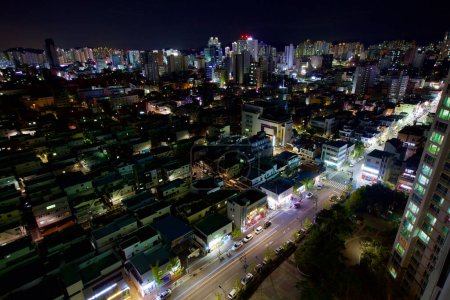 Foto de Capturada del piso 24 de un apartamento, esta imagen muestra las calles de Ulsan por la noche, con edificios bajos iluminados y edificios de apartamentos altos en la distancia. - Imagen libre de derechos