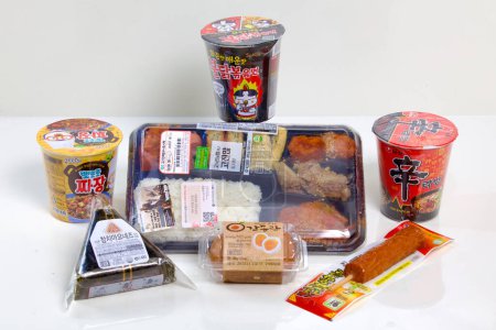 Foto de Una selección de opciones de almuerzo de una tienda surcoreana de conveniencia, con una lonchera, ramen, barra caliente (carne en palo), huevos y triángulo gimbap. - Imagen libre de derechos