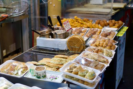 Foto de Una deliciosa variedad de aperitivos rápidos, incluyendo gofres crujientes y mandú salado, ofrece un sabor de la comida callejera local en un mercado tradicional coreano. - Imagen libre de derechos