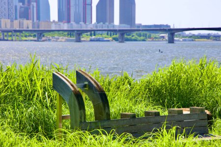 Photo for The 'Playscape' installation in Hangang Art Park features a resting bench crafted with traditional wooden shipbuilding techniques, with a paddleboarder on the Han River visible in the background. - Royalty Free Image