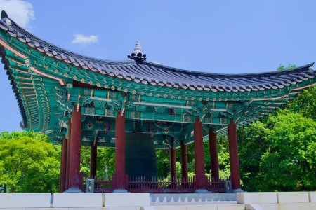 Foto de Un pabellón tradicional que alberga una campana histórica se encuentra elegantemente en el parque que rodea el Museo Nacional de Corea, ofreciendo un vistazo al rico pasado cultural de Corea.. - Imagen libre de derechos