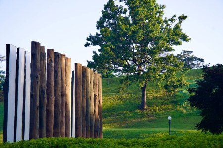 Photo for Seoul, South Korea - June 2, 2023: An intriguing art installation of five-meter tall halved wood posts with white-painted insides, set against the green lawns and a sloping hill of Olympic Park. - Royalty Free Image