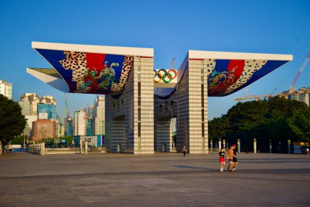 Photo for Seoul, South Korea - June 2, 2023: Early morning joggers cross the courtyard of Olympic Park, with the World Peace Gate illuminated by sunrise in the background. - Royalty Free Image