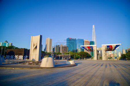 Photo for Seoul, South Korea - June 2, 2023: A wide-angle view capturing a concrete sculpture in Olympic Park, with the World Peace Gate and Lotte Tower in the background. - Royalty Free Image