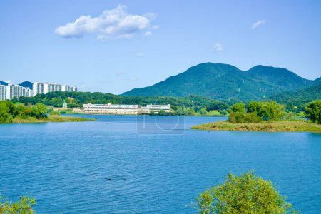 Photo for Hanam City, South Korea - October 1, 2023: A panoramic view across the wide Han River, featuring a sandy and green island, set against a backdrop of mountains under a clear blue sky. - Royalty Free Image