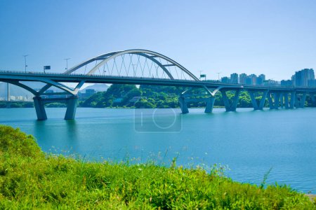 Photo for Guri City, South Korea - September 30, 2023: The majestic Guri Amsa Bridge spans the Han River, showcasing a picturesque daytime view with Hanam City's silhouette against a clear blue sky. - Royalty Free Image