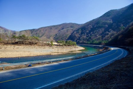 Foto de Mungyeong City, Corea del Sur - 10 de febrero de 2021: La carretera curva del área de Jinnamgyoban corre junto al río Yeong, con montañas que se elevan a su lado, ofreciendo senderos cerca de sitios históricos. - Imagen libre de derechos