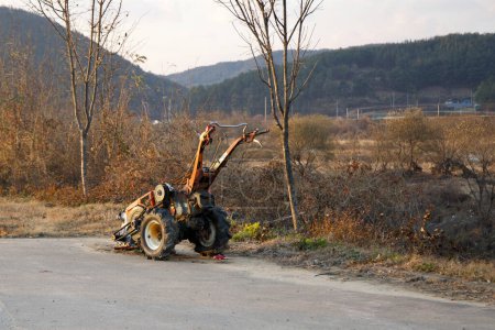 Photo for Sangju City, South Korea - November 18th, 2023: A rugged, motorized handplow rests by the side of a bike path and farm road in Sangju City, captured at dusk near the Nakdong River. - Royalty Free Image