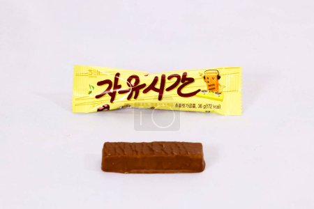 Photo for Ulsan, South Korea - January 14, 2024: A delicious chocolate almond candy bar labeled "Free Time" from the renowned company Haitai, with the package displayed above the chocolate bar, all set against a clean white background. - Royalty Free Image