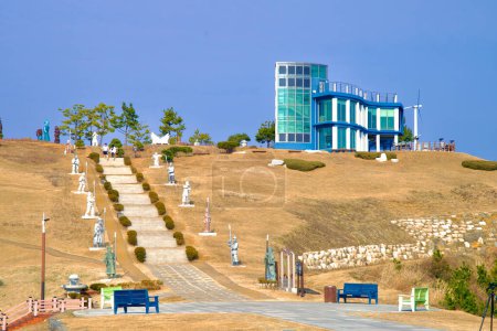 Foto de Samcheok City, Corea del Sur - 28 de diciembre de 2023: Escaleras que suben a un observatorio en una colina en Lady Suro Memorial Park, flanqueada por estatuas de soldados de la era Silla y rodeada de céspedes. - Imagen libre de derechos