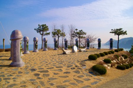 Téléchargez les photos : Samcheok City, South Korea - December 28, 2023: Intriguing two-meter tall stone penis sculptures with embedded Chinese zodiac animals, set in a courtyard against a backdrop of blue sky and the East Sea. - en image libre de droit