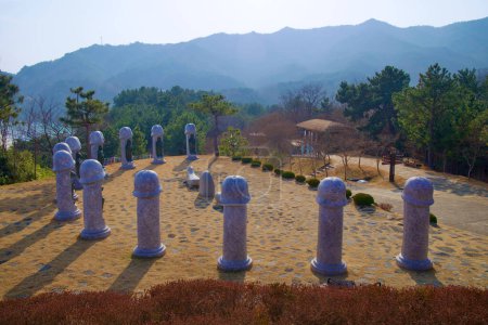 Téléchargez les photos : Samcheok City, Corée du Sud - 28 décembre 2023 : Sculptures uniques en pierre de deux mètres de haut en forme de pénis, chacune entourée d'un animal du zodiaque chinois, dans une cour avec des montagnes en arrière-plan. - en image libre de droit