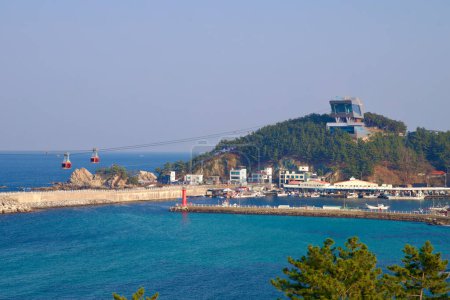 Foto de Samcheok City, Corea del Sur - 28 de diciembre de 2023: Esta amplia vista captura el puerto de Jangho y sus serenas aguas desde una perspectiva más amplia, incluida la estación de teleférico en la cima de la colina. A continuación, el puerto bulle de actividad, flanqueado por el icónico lightho - Imagen libre de derechos