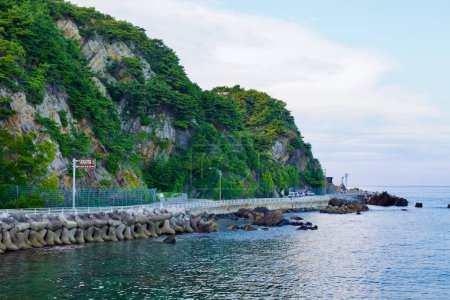 Photo for Gangneung City, South Korea - July 29th, 2019: Heonhwa Road winds along rocky hillsides with calm East Sea waters below, showcasing the serene beauty of South Korea's closest road to the sea. - Royalty Free Image