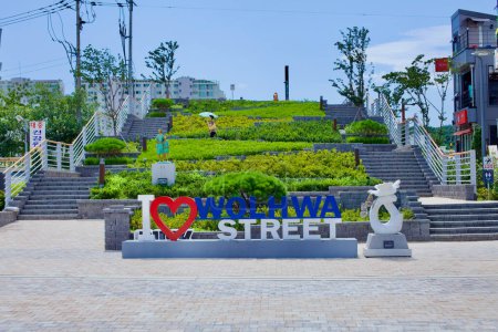 Foto de Gangneung City, Corea del Sur - 29 de julio de 2019: Al final de Wolhwa Street, una escalera flanqueada por un exuberante paisaje verde y con un cartel que proclama "I heart Wolhwa Street" lleva a los visitantes hacia Namdae Stream. - Imagen libre de derechos