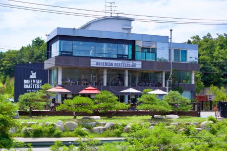 Téléchargez les photos : Gangneung City, Corée du Sud - 29 juillet 2019 : Niché au milieu d'arbres verts avec une pelouse soignée, le café Bohemian Roasters de trois étages offre une expérience artisanale de café goutte à goutte le long de la côte pittoresque de la ville. - en image libre de droit