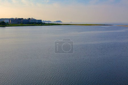 Foto de Condado de Yangyang, Corea del Sur - 30 de julio de 2019: Una pintoresca vista al atardecer en el arroyo Yangyang Namdae, donde las aguas tranquilas se encuentran con el Mar del Este, flanqueado por hoteles y una desembocadura de arroyo arenoso. - Imagen libre de derechos