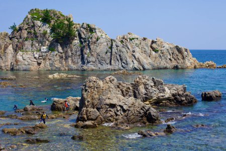 Photo for Goseong County, South Korea - July 30, 2019: A towering rock formation, 30 meters tall and 180 meters long, rises from the East Sea just off the coast near Geojin Port and Geojin 1-ri Beach. Adventurers, clad in lifejackets, wade and snorkel in the s - Royalty Free Image
