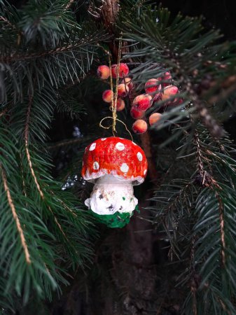Photo for Beautiful mushroom toy on the Christmas tree in the forest. The green branches of the Christmas tree are decorated with Christmas ornaments. Christmas tree toy amanita. - Royalty Free Image