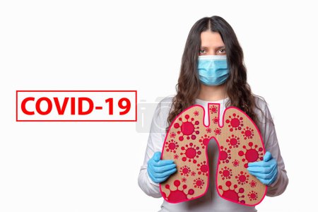 Photo for Covid-19 coronavirus infects the lungs with bilateral pneumonia. Girl in a protective mask holds the lungs with bacteria SARS-CoV-2. - Royalty Free Image