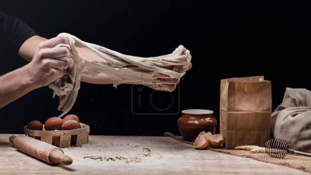Photo for A man is cooking bread. The baker pulls the dough with his hands. Preparation of bread dough. The concept of homemade food. - Royalty Free Image