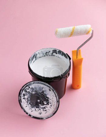 Foto de Lata de pintura blanca y un rodillo sobre fondo rosa. Concepto creativo de renovación del hogar. - Imagen libre de derechos