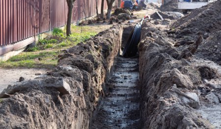 Earthwork. A deep long trench dug in the ground for laying cables, pipes. Telecommunications industry.