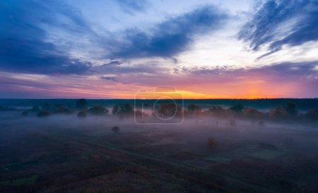 Paisaje matutino al amanecer con niebla en un campo con hermoso cielo nublado.