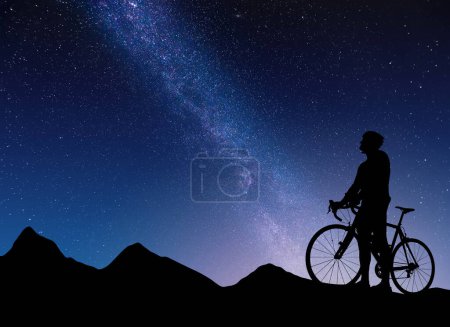 Photo for Silhouette of a cyclist against the backdrop of mountains and starry sky with the Milky Way. - Royalty Free Image